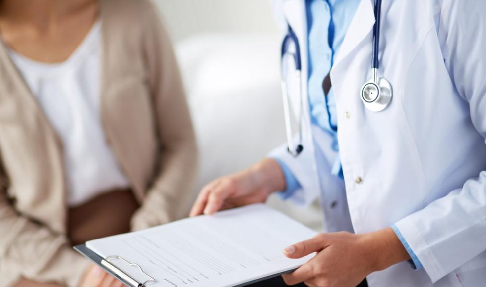 Female doctor holding application form while consulting patient