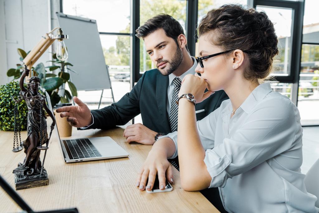 Lawyers discussing work at workplace with laptop