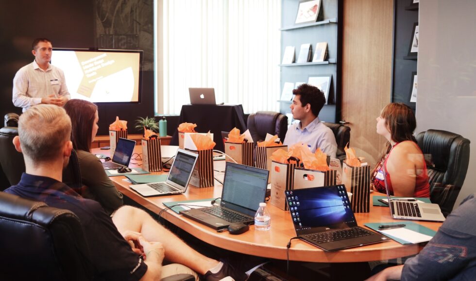 man standing in front of people sitting beside table with laptop computers